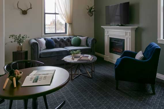 Cozy living room with a tufted gray sofa, blue chair, fireplace, and wall-mounted TV.